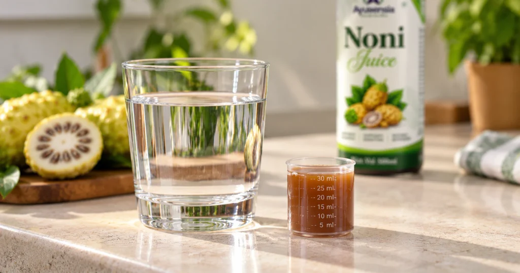 Measuring cap with 30 ml of Ayusensia Noni Juice next to a glass of water